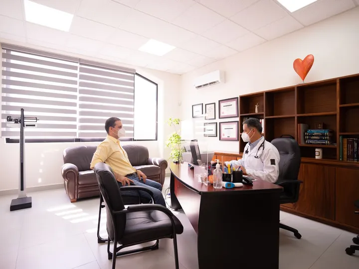 Médico y paciente conversando durante una consulta en el consultorio
