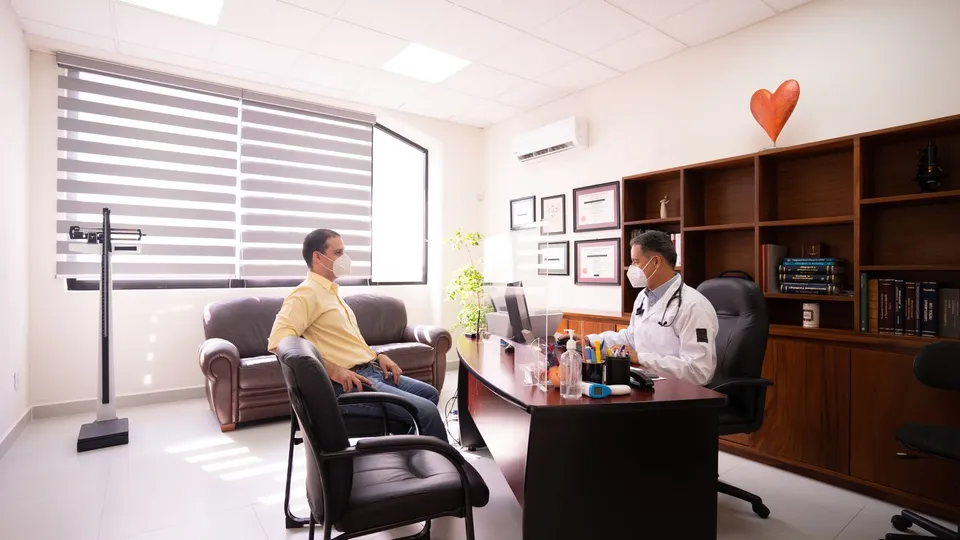 Médico y paciente conversando durante una consulta en el consultorio
