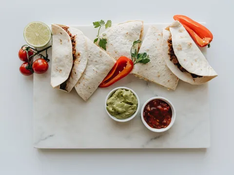 Tacos servidos en una tabla con guacamole y salsa